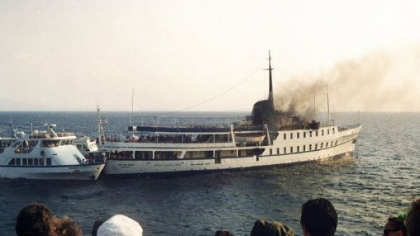 مارة ينظرون الى السفينة "سيتي اوف بوروس" والدخان يتصاعد منها في 11 تموز/يوليو 1988
