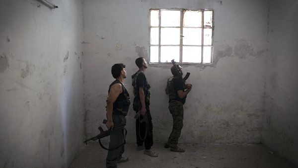 Rebel fighters look at the pro-government forces' positions through a window as they hold a position in an empty room in the Salaheddine district of the northern Syrian city of Aleppo, on July 9, 2013. (Source: AFP/JM LOPEZ)