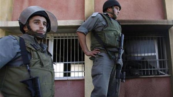 شرطيون اسرائيليون يقفون بجوار نافذة مكسورة لمسجد