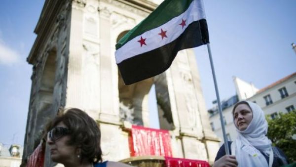 متظاهرة ضد النظام السوري ترفع العلم السوري ما قبل حكم البعث في باريس 
