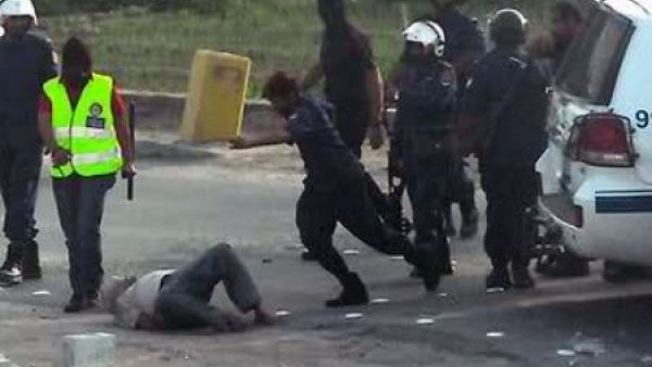 ارشيف/ رجل امن يهاجم متظاهرا مسجى على الارض خلال تفريق تظاهرات سابقة في المنامة