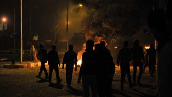 Egyptian protesters stand near burning tyres outside the main security headquarters in the canal city of Port Said early on Tuesday. (Photo: AFP/STR) 