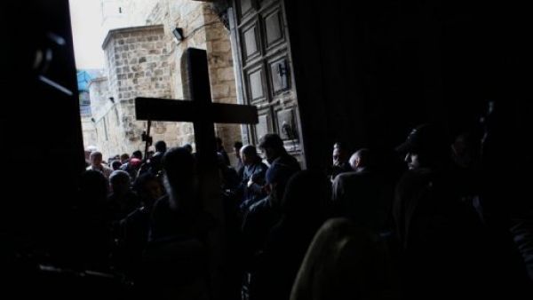 حجاج مسيحيون يدخلون كنيسة القيامة رافعين صلبانا
