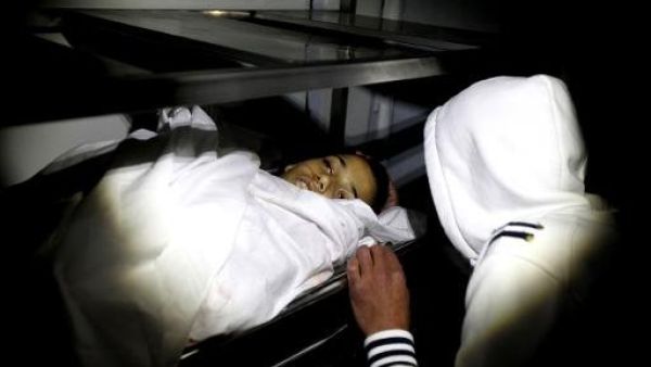 احد اقارب الفتى الفلسطيني وجيه الرمحي يلقي نظرة على جثته في مخيم الجلزون بالضفة الغربية
