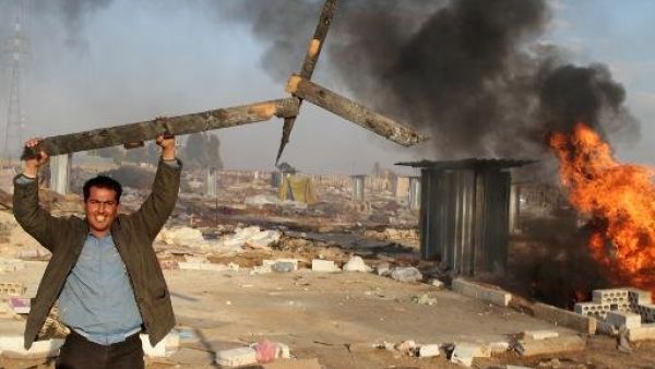 رجل يحمل قطعة خشب مكسورة من مخيم للاجئين السوريين احرقه السكان المحليون في شرق لبنان
