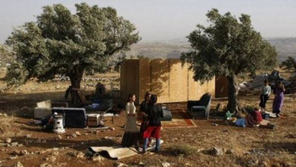 مستوطنون يقفون الى جانب كوخ من الخشب اعيد بناؤه في مستوطنة ميغرون العشوائية في الضفة الغربية 
