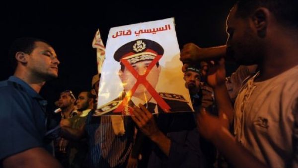 ارشيف/ انصار الرئيس المصري المعزول محمد مرسي يحملون صوررة تصف قائد الجيش عبدالفتاح السيسي قاتلا