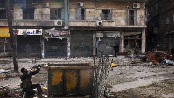 A Syrian rebel aims his weapon as he takes position behind a makeshift barricade during clashes with regime forces in the Salaheddine district of Aleppo in northern Syria on Saturday. (Photo: AFP / JM LOPEZ)