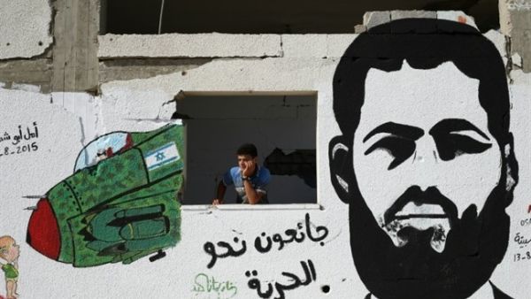 A young Palestinian stands next to a graffiti portrait of Muhammad Allan, who was rearrested following a hunger strike that lasted longer than two months. (AFP/File) A young Palestinian stands next to a graffiti portrait of Muhammad Allan, who was rearrested following a hunger strike that lasted longer than two months. (AFP/File)