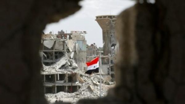 العلم السوري وسط الحطام عند مدخل حي الحجر الأسود عند الأطراف الجنوبية لدمشق
