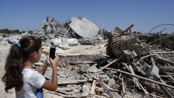 A Palestinian girl photographs the rubble of a home demolished by the IDF on July 26, 2016. (AFP/Ahmad Gharabli)