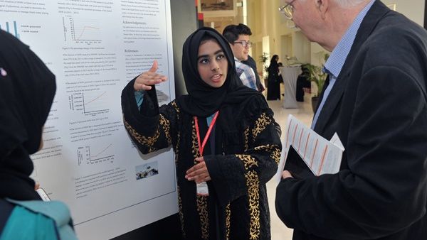 طالبة من مدرسة برايت فيوتشر الدولية تشرح نتائج الملصق العلمي لعضو لجنة التحكيم الدكتور ديتريتش بيزيلبيرغ.