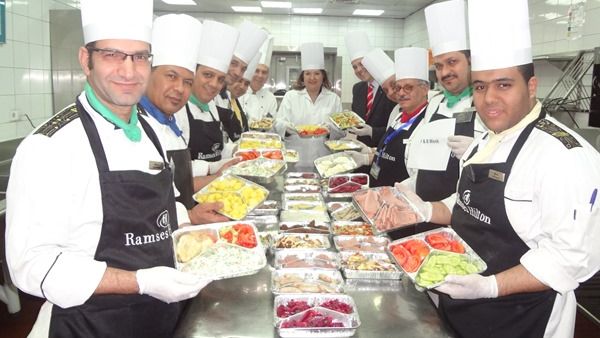 Soha El Torgoman, Ramses Hilton General manager with the kitchen brigade while preparing the packed meals ready for distribution.