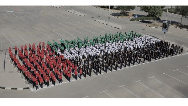شارك أكثر من 600 طالب من مدرستي كويلا وجي اس اس الدولية تتراوح أعمارهم ما بين السابعة ولغاية الحادية عشر في تشكيل علم بشري بألوان زاهية.