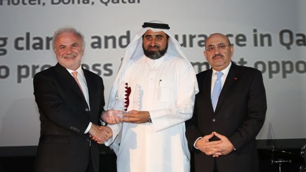 المهندس جاسم تلفت، المدير التنفيذي للمجموعة في الإدارة العامة للمشاريع الرئيسية والإدارة العامة للمرافق في مؤسسة قطر (وسط) يتسلم الجائزة من قبل السيد إدموند اوسوليفان، رئيس مجلس إدارة ميد (يسار) بحضور السيد جبرا رجا غندور، المدير التنفيذي لبنك قطر الدولي