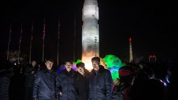 A group of men stand before an ice sculpture depicting a Hwasong-15 intercontinental ballistic missile (ICBM) at the Pyongyang Ice Sculpture Festival on New Year's Eve. (AFP) 