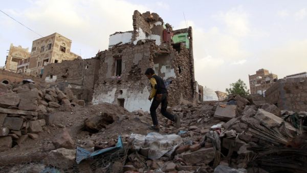 A Yemeni boy runs on March 23, 2016 past buildings that were damaged by air strikes carried out by the Saudi-led coalition over the past year in the UNESCO-listed old city of the Yemeni capital Sanaa. (AFP/Mohammed Huwais)