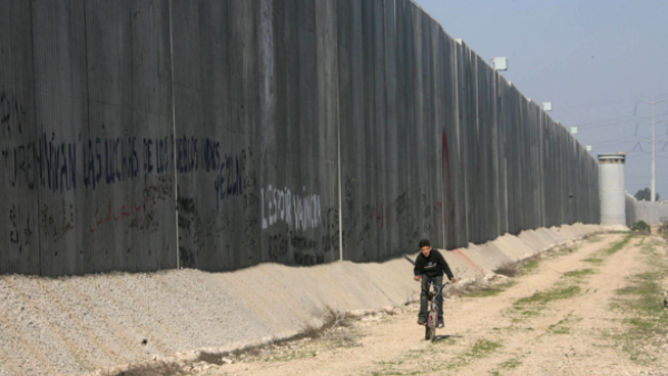 A child rides his bicycle alongside a separation wall in the West Bank. (AFP/File)