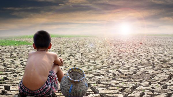 Sad boy sitting on dry ground and sunset . (Shutterstock/ File Photo)