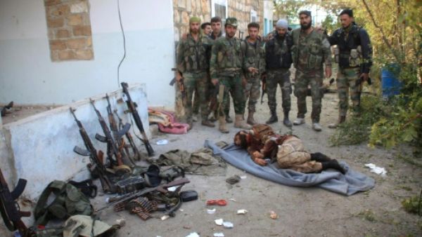 جنود من الجيش السوري يقفون امام جثة مقاتل اسلامي

