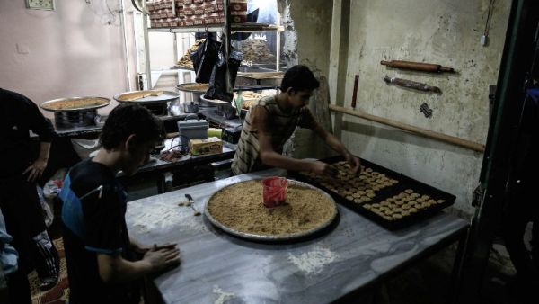 Syrians preparing traditional sweets for Ramadan in a bakery on June 28, 2016. (AFP/Sameer Al-Doumy)