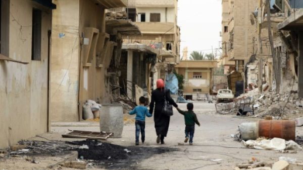 امراة وطفلاها يسيرون في شارع بمدينة تدمر السورية