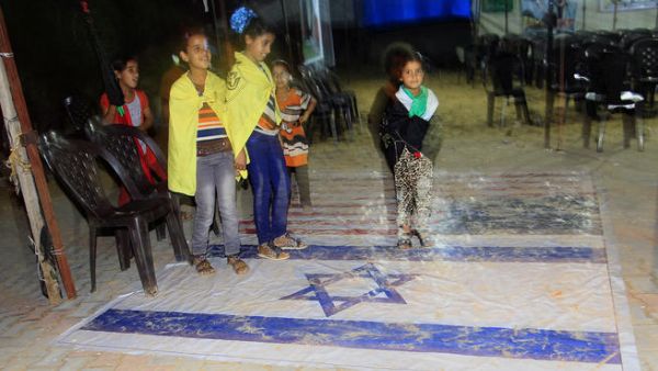 Young Palestinian relatives of freed Palestinian prisoner Ateya Abu Moussa, who was held by Israel for 20 years, stand on Israeli and US flags upon arrival at his family's house in Khan Younis in the southern Gaza Strip (AFP/SAID KHATIB)