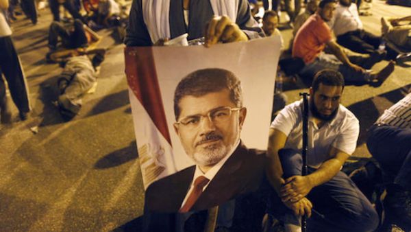  An Egyptian supporter of the Muslim Brotherhood holds a portrait of deposed president Mohamed Morsi during a rally outside Cairo's Rabaa al-Adawiya mosque late on July 7, 2013. (Source: AFP/MAHMOUD KHALED)
