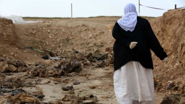 A Yazidi woman stands next to an unearthed mass grave in northern Iraq (Safin Hamed/AFP)
