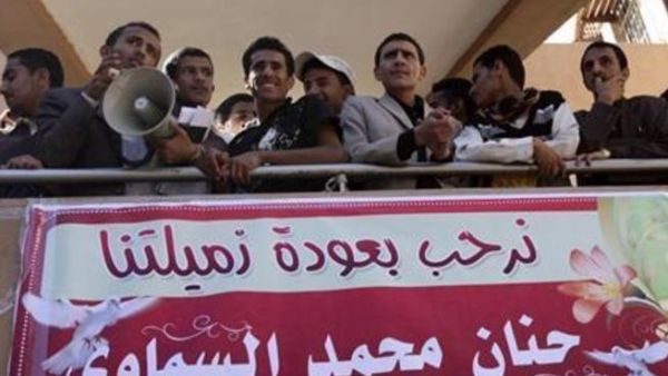 طلاب يقفون اعلى لافتة ترحب بعودة الطالبة حنان السماوي الى جامعة صنعاء
