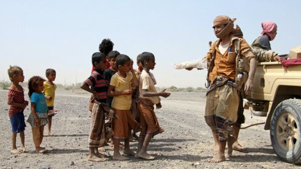 Pro-government fighters give food to Yemeni children on the road leading to the southwestern port city of Mokha on January 26, 2017. (AFP/Saleh al-Obeidi)