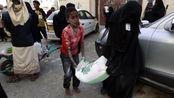 Yemenis affected by the country's ongoing conflict receive food rations provided by an initiative organized by a local charity in the capital Sanaa on June 2, 2016. (AFP/Mohammed Huwais)