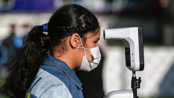 تلميذة فلسطينية في قطاع غزة تضع كمامة وتخضع لفحص حرارتها في مدرسة خاصة