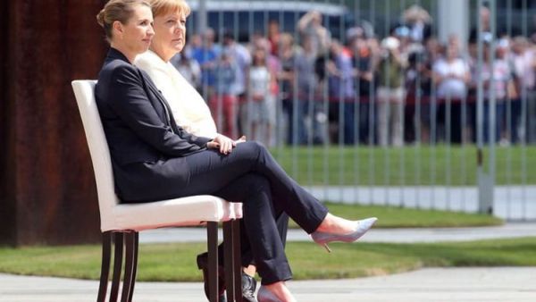 ميركل المرتجفة تجلس على كرسي أثناء عزف النشيد الوطني