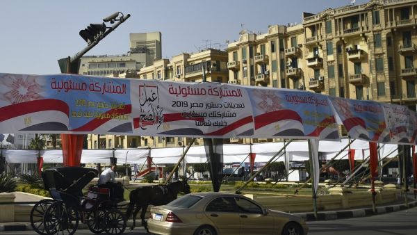Egyptians pass under banners reading in Arabic "Do what is right", and "Participation is your responsibility", urging voters to participate in the upcoming referendum for the constitutional amendments, in Cairo (AFP)