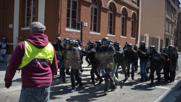 Police officers run in lines as they face a "Yellow vest" (Gilets Jaunes) protester  (AFP)