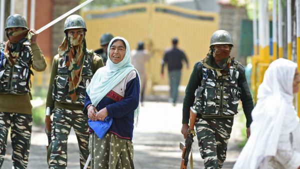 Indian paramilitary troopers patrol as a Kashmiri woman voter looks on in Srinagar  (AFP)