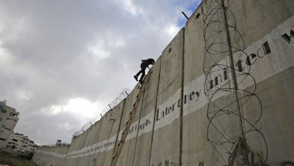 Palestinian youths climb a section of Israel's separation wall to reach at the al-Aqsa Mosque compound in Jerusalem (AFP)
