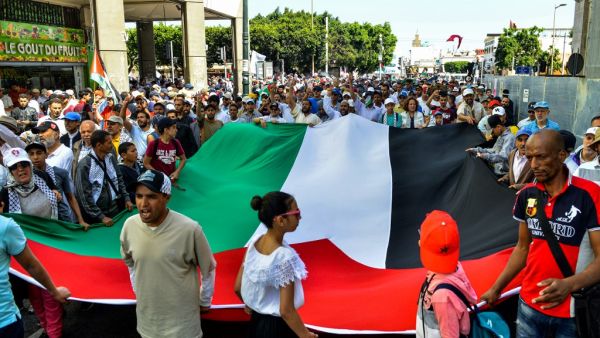 Protesters chant slogans and wave a giant Palestinian flag as they march in a demonstration in the Moroccan capital Rabat  (AFP)