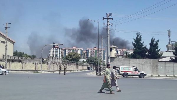 Afghan men walk on a road as smoke rises from the site of an attack in Kabul  (AFP)