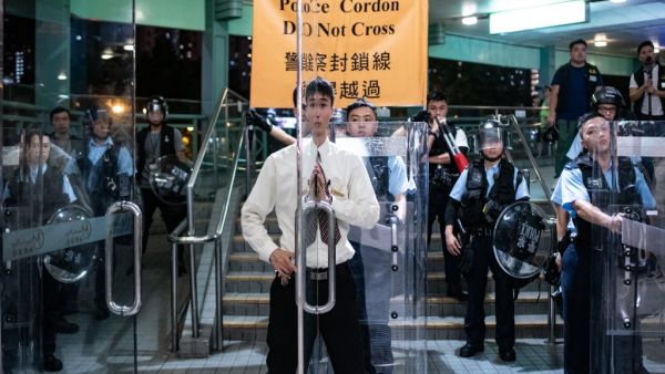 A security guard (C) closes the door of the shopping arcade as riot police stand guard at a footbridge during an anti-parallel trading protest in Sheung Shui district in Hong Kong  (AFP)