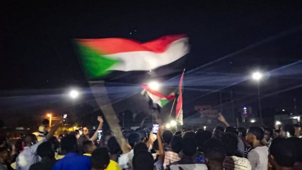 Sudanese demonstrators wave national flags as they protest in the streets of the capital Khartoum to demand civilian rule  (AFP)