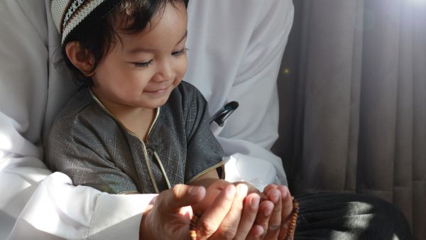 Muslim Man teaching his little son to pray to God (Shutterstock)	