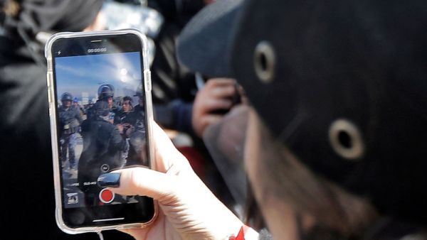 A woman films clashes in Beirut, Jan 2020 /AFP