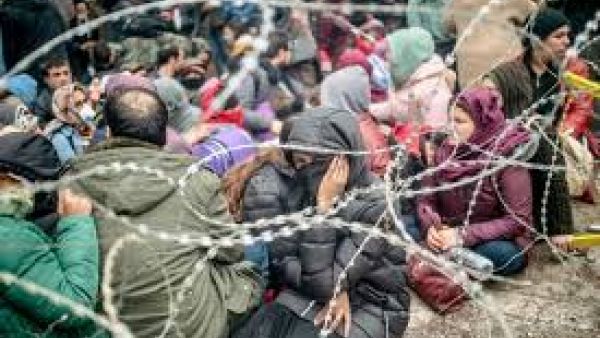 Migrants behind barbed wire fence in buffer zone along Turkey-Greece border /AFP