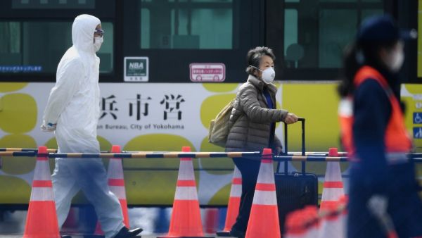 A passenger (C) leaves after disembarking from the Diamond Princess cruise ship - in quarantine due to fears of the new COVID-19 coronavirus - at the Daikoku Pier Cruise Terminal in Yokohama on February 19, 2020. afp