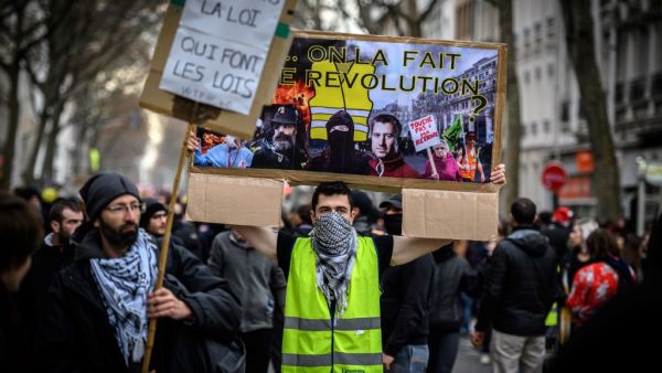 A man wearing a yellow vest (gilet jaune) holds a placard reading "we are going to do the revolution" as he takes part in a demonstration in Lyon on December 17, 2019 to protest against French government's plan to overhaul the country's retirement system, as part of a national general strike. (AFP/ File Photo)