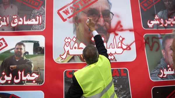A Libyan man wearing yellow vest, spray-paints an image of strongman Khalifa Haftar during a demonstration against the military commander in the capital Tripoli's Martyrs' Square on April 26, 2019.  FADEL SENNA / AFP