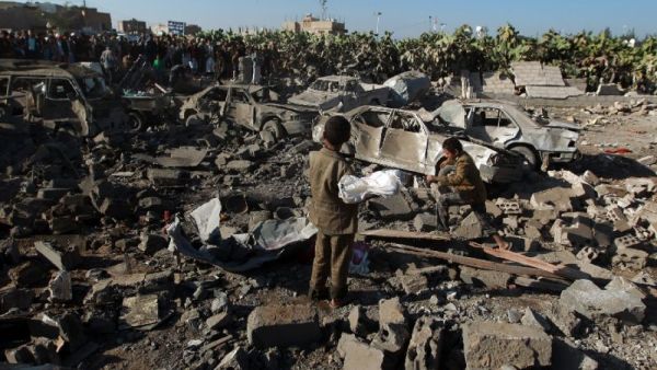Yemeni civilians stand at the site of a Saudi air strike against Huthi rebels near Sanaa Airport on March 26, 2015 (AFP Photo/Mohammed Huwais)