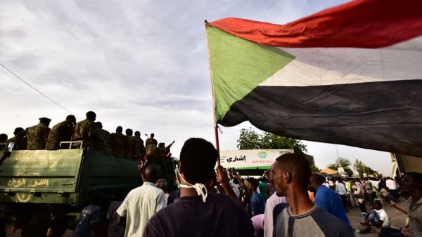Sudanese demonstrators gather as an army vehicle drives by, near the military headquarters in the capital Khartoum on April 14, 2019. (AFP)